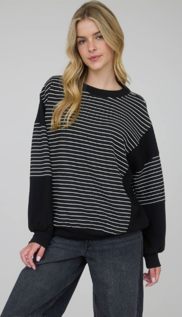 Woman wearing a black and white striped sweater with a plain background